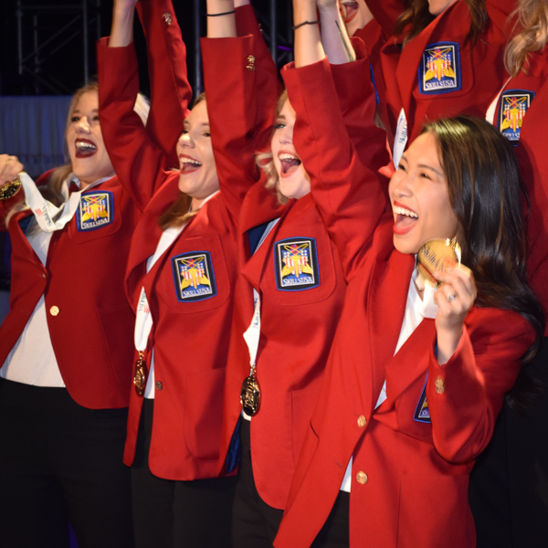 Students with hands raised in excitement and holding winning medal